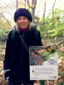 Author Lynne Cherry next to sign with her illustration from "Flute's Journey: The Life of a Wood Thrush"